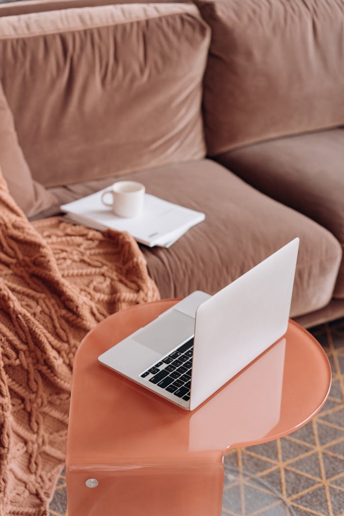 A modern laptop on a stylish table with warm decor in a comfortable living room setting.